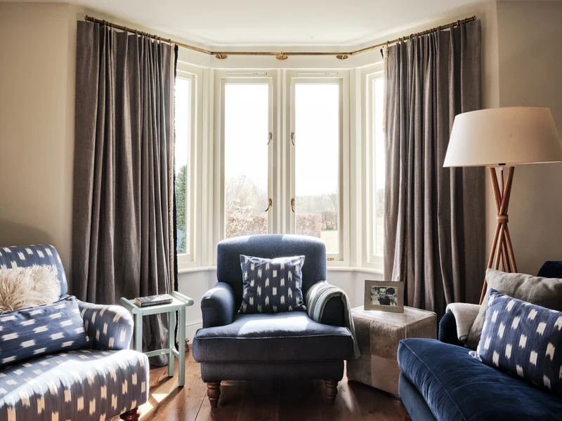 Blue armchairs and sofa around a bay window