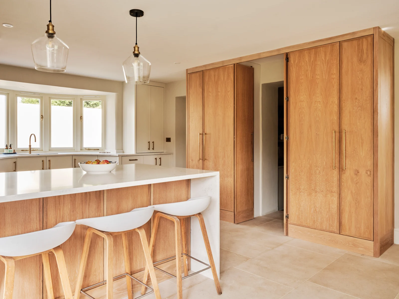 Oak kitchen cabinetry and a pale island with timber stools