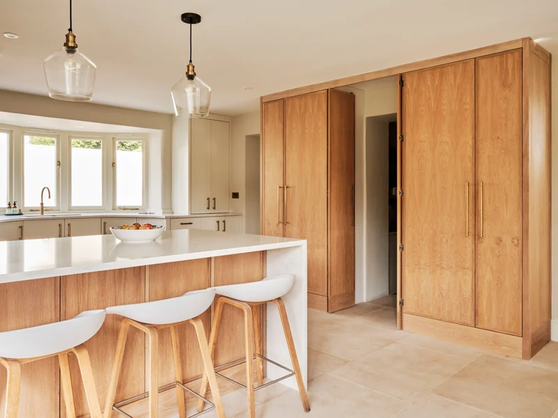 Oak kitchen cabinetry and a pale island with timber stools