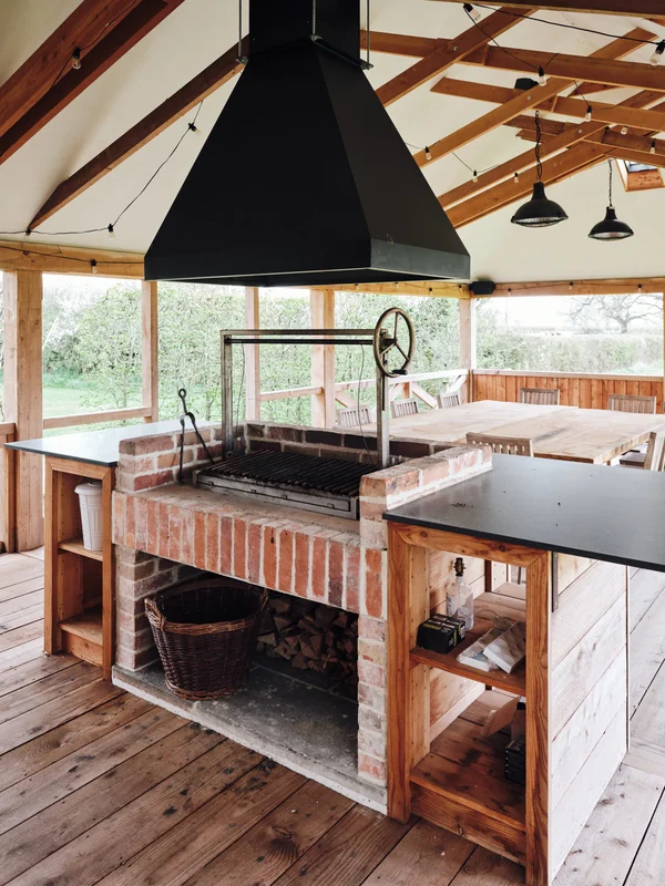 Brick-built outdoor grill beneath exposed timber rafters
