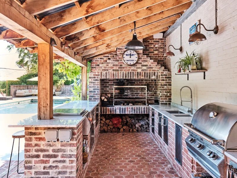 Covered outdoor kitchen with brick grill and garden views