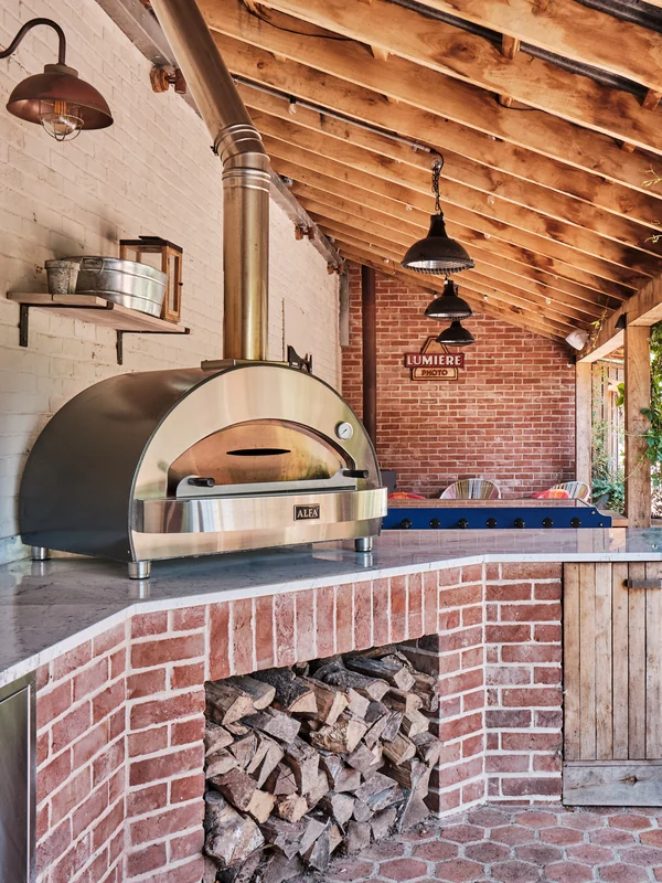 Brick pizza oven and outdoor kitchen beneath a timber roof