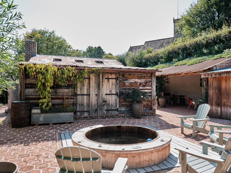 Circular hot tub beside reclaimed-timber garden buildings